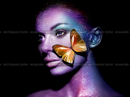 Fashion model woman in bright sparkles and neon lights posing in studio. Portrait of beautiful woman with butterfly. Art design glitter glowing make up. Стоковое фото, агентство Ingram Publishing / Фотобанк Лори