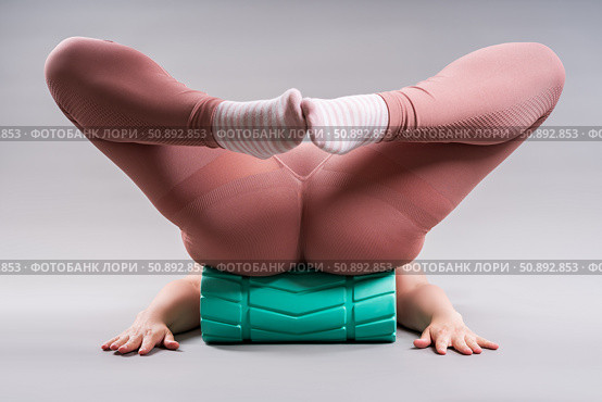 Fat woman in sportswear use myofascial release massage mfr roll on gray background, pelvic floor muscle exercise. Стоковое фото, фотограф Станислав Тарко / Фотобанк Лори
