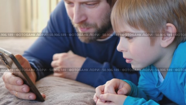 Father and son little boy laughing and using phone. They watching funny videos together, playing games on smartphone. Concept technology, smartphone addicted. Fun weekend activity. Modern fatherhood. Стоковое видео, видеограф Марина Демидюк / Фотобанк Лори