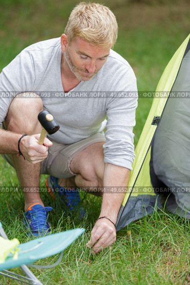 father putting up tent on camping trip. Стоковое фото, агентство Ingram Publishing / Фотобанк Лори