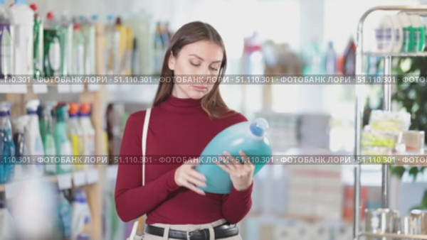 Female buyer chooses a high-quality fabric softener in the household section of a supermarket. Стоковое видео, видеограф Яков Филимонов / Фотобанк Лори