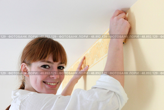 Female decorator hanging wallpaper border. Стоковое фото, агентство Ingram Publishing / Фотобанк Лори