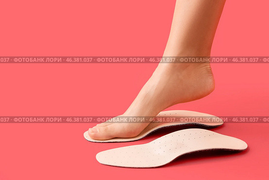 Female foot and orthopedic insoles on red background. Стоковое фото, фотограф Pixel_shot / Фотобанк Лори