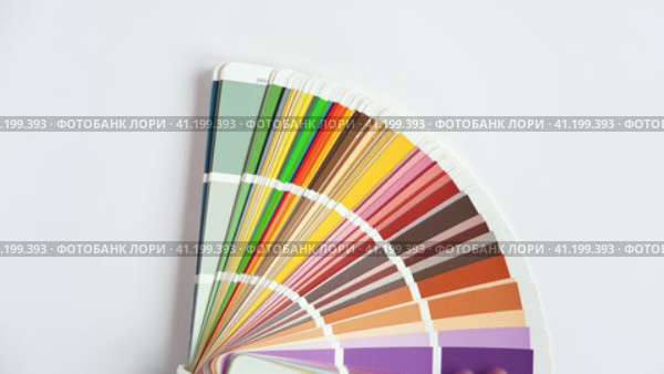 Female Hand opening Color guide close up. Assortment of Colour samples for design. Colors palette fan on white concrete wall background. Graphic designer chooses colors. Coloured swatches catalogue 4K. Стоковое видео, видеограф Марина Демидюк / Фотобанк Лори