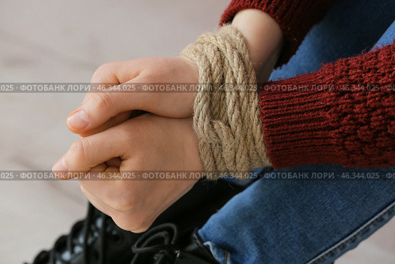 Female hostage with tied hands sitting on floor in room, closeup. Стоковое фото, фотограф Pixel_shot / Фотобанк Лори