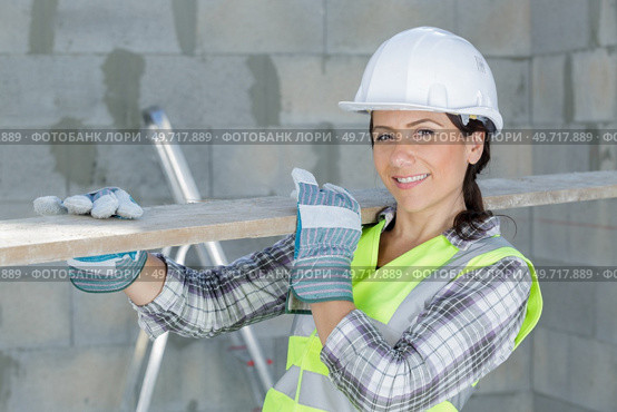 female labourer carrying length of wood on her shoulder. Стоковое фото, агентство Ingram Publishing / Фотобанк Лори
