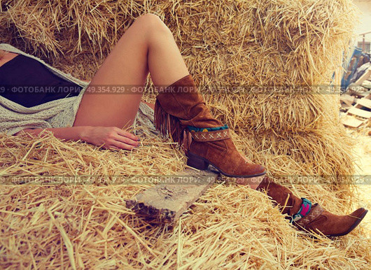 female legs with leather brown on straw bale. female legs with leather brown boots relaxed on straw bale barn. Стоковое фото, агентство Ingram Publishing / Фотобанк Лори