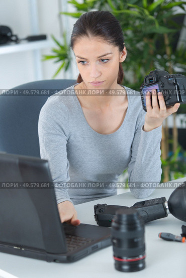 female photographer sitting on the desk with laptop. Стоковое фото, агентство Ingram Publishing / Фотобанк Лори