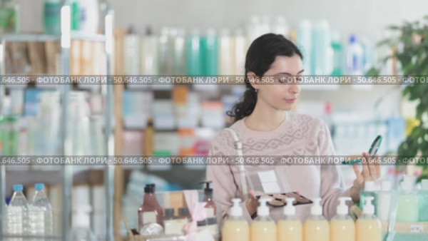 Female shopper in autumn clothes chooses best cosmetic in supermarket. Стоковое видео, видеограф Яков Филимонов / Фотобанк Лори