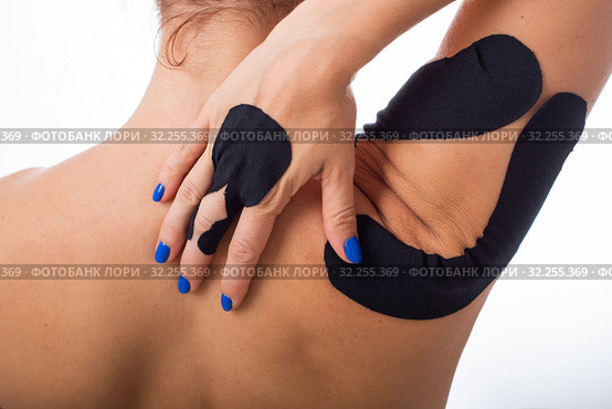 Female shoulder with kineziotape on a white background. Alternative medicine for sports injuries of joints and ligaments. Young sportswoman with a black Medical taping on a sore shoulder and finger. Стоковое фото, фотограф Михаил Решетников / Фотобанк Лори