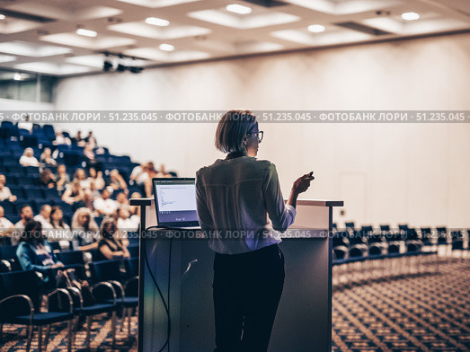 Female speaker giving a talk on corporate business conference. Unrecognizable people in audience at conference hall. Business and Entrepreneurship event. Стоковое фото, фотограф Matej Kastelic / Фотобанк Лори