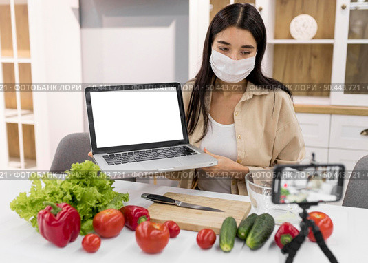 female vlogging home with vegetables laptop. Стоковое фото, агентство Ingram Publishing / Фотобанк Лори