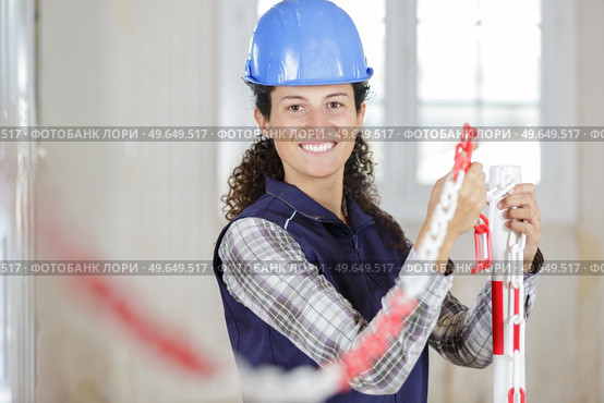 female worker erecting exclusion chain in renovation property. Стоковое фото, агентство Ingram Publishing / Фотобанк Лори