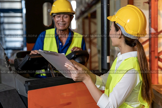 Female young asian warehouse workers discuss about inventory to male worker who operate forklift in large distrubution warehouse background. Reopening business warehouse inventory and logistic concept. Стоковое фото, агентство Ingram Publishing / Фотобанк Лори