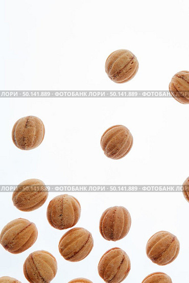 Feshly baked homemade cakes in a shape of walnuts filled milk cream on a white background with copy space.. Falling homemade cookies walnuts on a white background. Стоковое фото, агентство Ingram Publishing / Фотобанк Лори