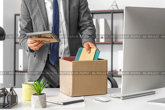 Fired young man packing his stuff in office. Стоковое фото, фотограф Pixel_shot / Фотобанк Лори