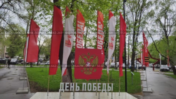 Флагшток с флагами к 80 летию со Дня Победы в Великой Отечественной Войне. Флаги развеваются на ветру в Кировском сквере. Россия, Вологда, 23 мая 2025. Flagpole with flags dedicated to 80th anniversary of Victory in Great Patriotic War. Flags fluttering in wind in Kirovsky Park. Inscription in Russian is Victory Day. Russia, Vologda, May 23, 2025. Редакционное видео, видеограф Ирина / Фотобанк Лори