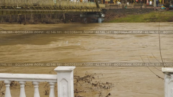 Flooding a brown muddy river. A fast flowing stream after heavy rain. A dangerous river threatening to rise to level of a footbridge. Environmental disaster. A global warming problem. Weather disaster. Стоковое видео, видеограф Воловодов Владимир / Фотобанк Лори