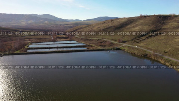 Flying over a hilly rural landscape with a winding road and fish ponds. Стоковое видео, видеограф Сергей Пристяжнюк (Serg Zastavkin) / Фотобанк Лори