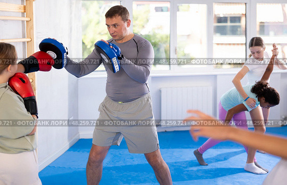 Focused girl hitting the focus mitts held by his boxing trainer in gym. Стоковое фото, фотограф Яков Филимонов / Фотобанк Лори