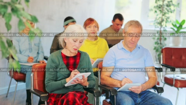 Focused motivated older woman and man listening to lecture in auditorium with group. Seniors education concept. Стоковое видео, видеограф Яков Филимонов / Фотобанк Лори