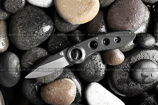 Folding pocket knife with rubberized handle on rocks background. Стоковое фото, фотограф Pixel_shot / Фотобанк Лори