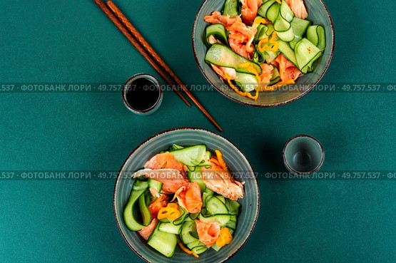 Fresh Asian salad with smoked salmon, fresh cucumber and chopstick. Top view.. Fish salad with raw cucumber. Стоковое фото, агентство Ingram Publishing / Фотобанк Лори