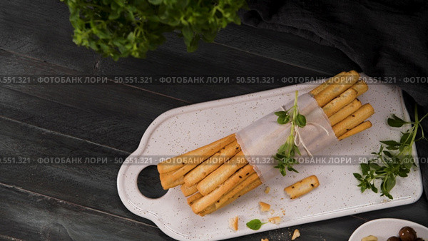 Fresh baked homemade grissini bread sticks in white ceramic tray with olive oil and basil herbs over kitchen counter top. Стоковое фото, агентство Ingram Publishing / Фотобанк Лори