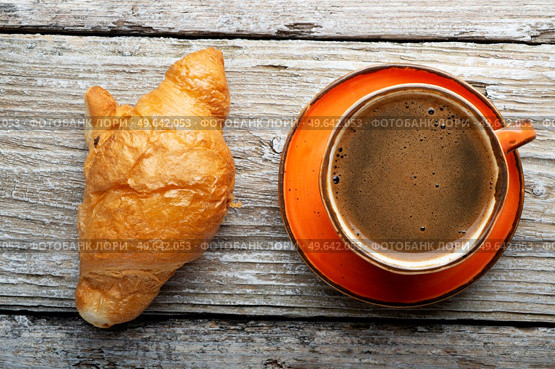 fresh boiled coffee served in beautiful orange cup with croissant around old style wooden background . close up. flat lay . Стоковое фото, агентство Ingram Publishing / Фотобанк Лори