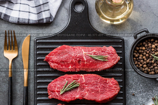 Fresh meat. Raw beef steaks with rosemary and spices on a stylish blackboard. Flat top view. Стоковое фото, фотограф Photojuli / Фотобанк Лори
