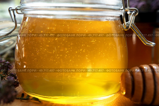 fresh natural  linden honey in big glass jar  at wooden tray with wooden  honey spoon around herb flowers. close up. . Стоковое фото, агентство Ingram Publishing / Фотобанк Лори