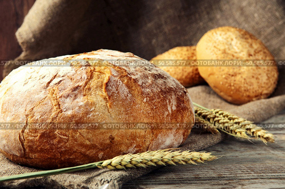 freshly baked loaf of homemade bread with wheat spikelets, lies on a wooden table. rustic style. closeup. Стоковое фото, агентство Ingram Publishing / Фотобанк Лори