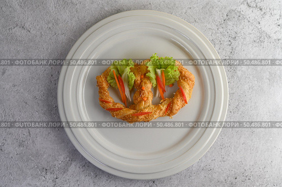 Freshly baked soft pretzel with generous sprinkling of coarse salt and sesame on white dish, decorate with lettuce and carrot beautifully, copy space. Стоковое фото, агентство Ingram Publishing / Фотобанк Лори