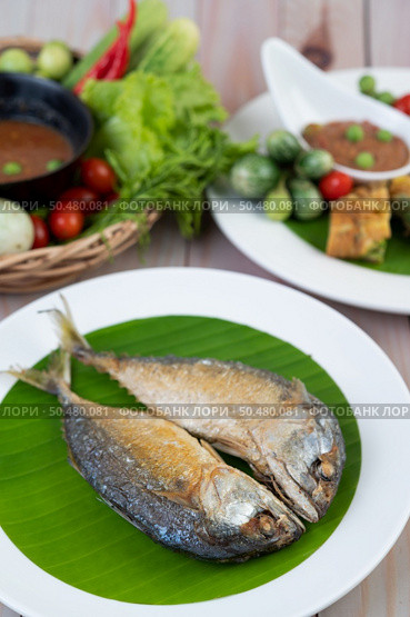 Fried mackerel placed on a white plate on a wooden floor. Стоковое фото, агентство Ingram Publishing / Фотобанк Лори