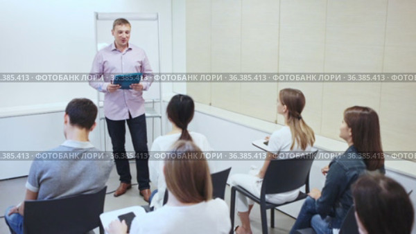 Friendly lawyer sitting with laptop in informal office meeting space, consulting his young female clients. Стоковое видео, видеограф Яков Филимонов / Фотобанк Лори