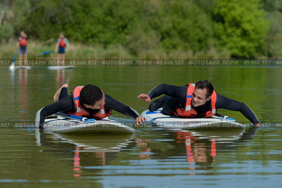 friends chating on stand up paddleboarding. Стоковое фото, агентство Ingram Publishing / Фотобанк Лори