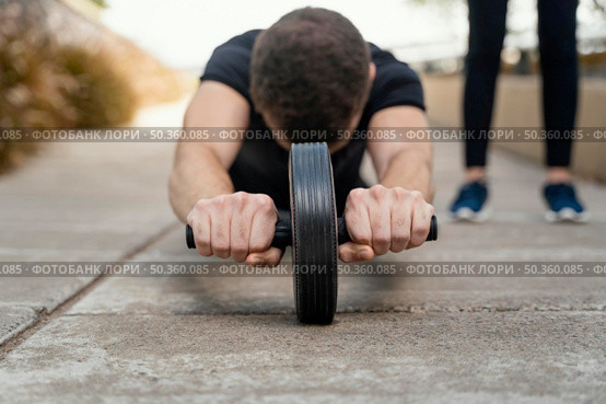 front view man exercising with ab wheel outdoors. Стоковое фото, агентство Ingram Publishing / Фотобанк Лори