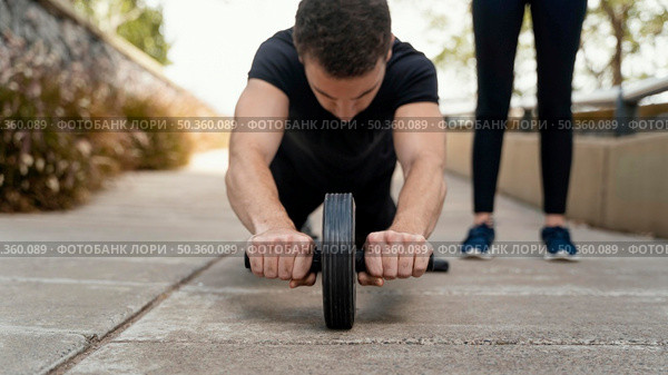 front view man exercising with ab wheel outside. Стоковое фото, агентство Ingram Publishing / Фотобанк Лори