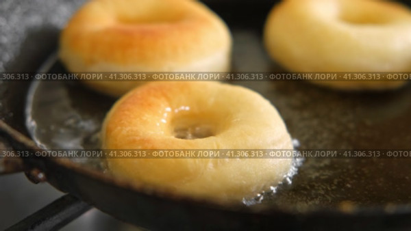 Frying process homemade and delicious donuts on fresh oil in a pan. Blue sugar topping on donuts in a home candy workshop. Pastry, sweet. Making dessert being deep fried. Preparation of donuts. Стоковое видео, видеограф Марина Демидюк / Фотобанк Лори