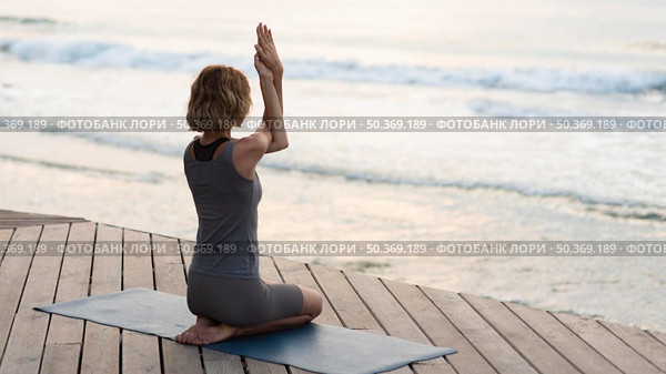 full shot woman doing yoga pose mat outside. Стоковое фото, агентство Ingram Publishing / Фотобанк Лори