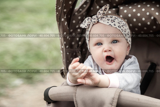 Funny bored baby with blue eyes sitting in stroller, sad looking at camera. Adorable pensive cute child infant yawns wide open mouth in pram. Concept of infancy, childhood emotion. Copy ad text space. Стоковое фото, фотограф Aleksandr Golubev / Фотобанк Лори