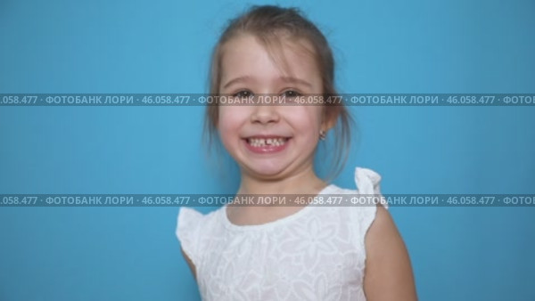 Funny little child girl try to taste fresh lemon, wrinkles and makes a grimace. Sour taste, facial emotions negative, in white dress, isolated blue background, copy space. Стоковое видео, видеограф Ирина Михайличенко / Фотобанк Лори