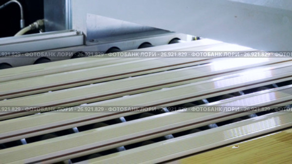 Furniture manufacture. Wooden parts covered with varnish are being unloaded on a specially equipped conveyor belt. 4K. Стоковое видео, видеограф ActionStore / Фотобанк Лори