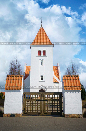 Gate to a beuatiful white church with red tiled roof under a blue sky. Стоковое фото, агентство Ingram Publishing / Фотобанк Лори