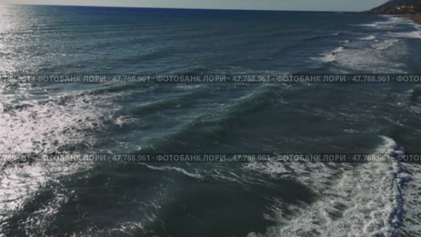 Gentle waves cascading over sandy beach, sunlight sparkling on rippling water surface, creating peaceful coastal scenery. Стоковое видео, видеограф ILIA GOROKHOV / Фотобанк Лори