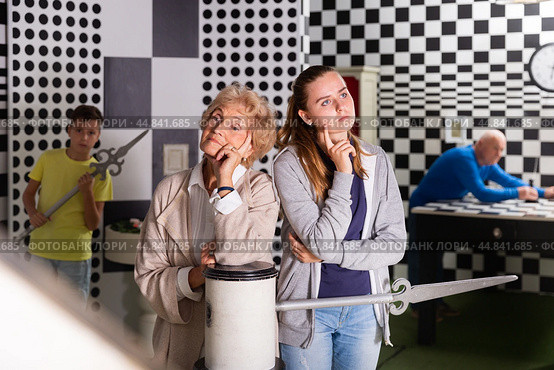 Girl and grandmother in quest room with friends, trying to find solution of conundrum. Стоковое фото, фотограф Яков Филимонов / Фотобанк Лори