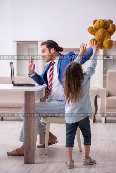Girl bothering young father during working from house in pandemi. Стоковое фото, фотограф Elnur / Фотобанк Лори