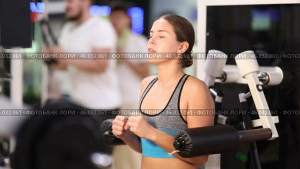 Girl in gym performs exercises for arm muscles using simulators and fitness center equipment. Стоковое видео, видеограф Яков Филимонов / Фотобанк Лори