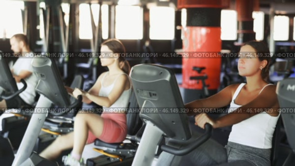 Girl performs exercises with stationary bicycle in gym. Стоковое видео, видеограф Яков Филимонов / Фотобанк Лори