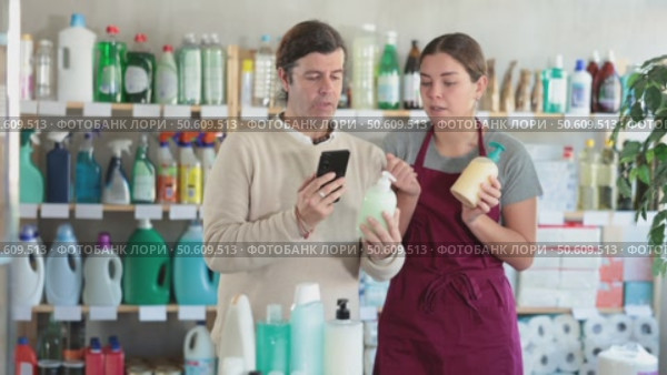 Girl seller help man visitor scan QR code, get information about liquid hand soap in mobile app. Стоковое видео, видеограф Яков Филимонов / Фотобанк Лори